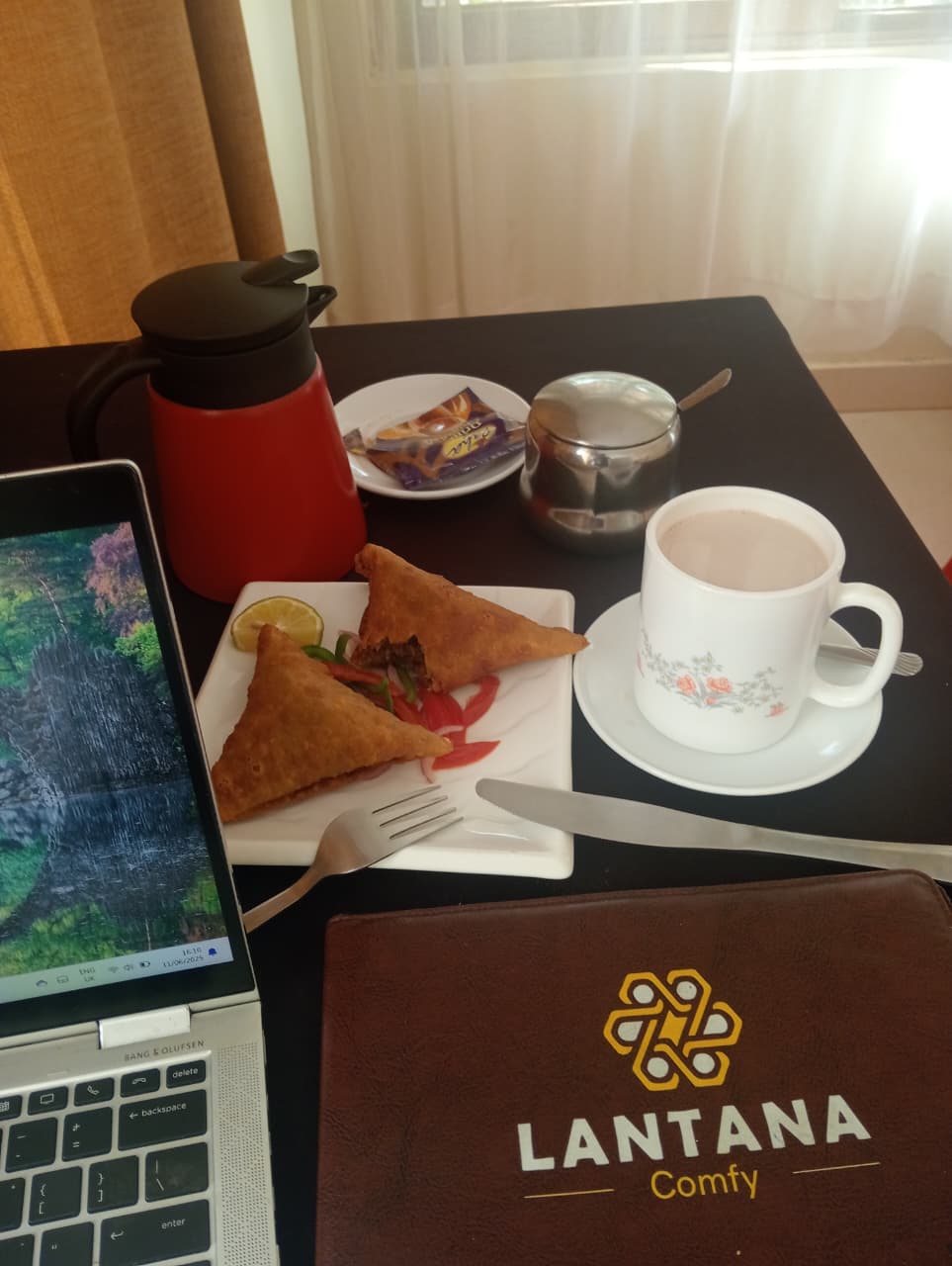 Tea and samosas beside a laptop and Lantana menu